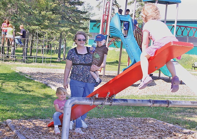 Anna Kridler of Elkhart, Indiana holds 2-year-old Alex and helps 4-year-old Abby at the Pickford Township Park on Tuesday as Abby and new playmate, Allie, have fun on the seesaw. The family is in the Eastern Upper Peninsula visiting relatives Bill and Jorene Krindler of Pickford.