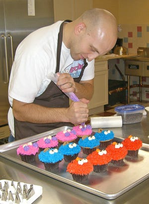 Mike Centamore, manager of Cupcake Charlie's on the Plymouth waterfront, next to the Weathervane restaurant, prepares a batch of Sesame Street cupcakes on special order.