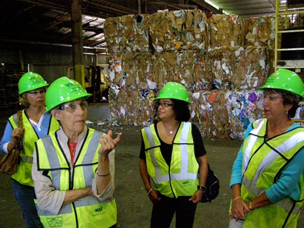 Island Women members Carol Konicki (from left), Anne Terry, Donna Davillier-Pace and Kay Hoffman stand in a warehouse full of bales of recycled cardboard. The group learned cardboard is one of the biggest moneymakers for Waste Management.
