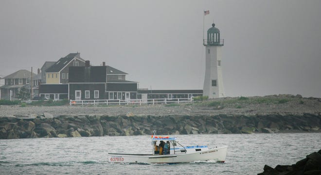 A lobster boat passes Scituate Light while heading out to sea from Scituate Harbor.
