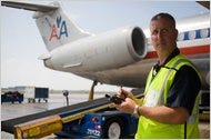 Ken Ihrig, a crew chief for American Airlines, manages luggage loading with a hand-held device.