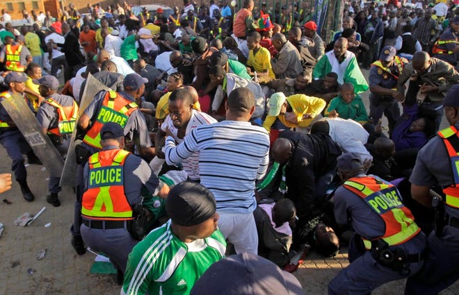 Police restrain fans prior to the warmup match between North Korea and Nigeria in Johannesburg, South Africa, Sunday June 6, 2010. Thousands of fans stampeded outside the stadium gates of a World Cup warmup game Sunday, five days before the start of soccer's showcase event. Several fans could be seen falling under the crush of people, many wearing Nigeria jerseys. Nigeria was playing North Korea at 10,000-seat Makhulong Stadium in suburban Johannesburg. (AP Photo/Frank Augstein)