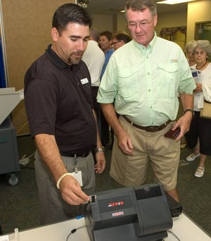 St. Johns County Supervisor of Elections worker Tony Solana demonstrates the county's new EViD election machine to Siegfried Fichte at an open house at the elections office on Tuesday. By PETER WILLOTT, peter.willott@staugustine.com