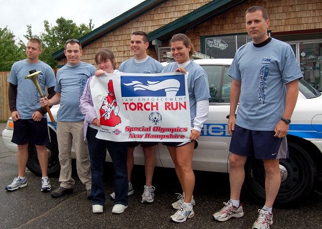 Special Olympian Arianna Johnston,14, of Laconia, holding banner on the left, stands with members of the Laconia Police Department who participated in the annual Special Olympics Torch Run on Thursday. Area law enforcement agencies helped run the flame along some 850 miles of New Hampshire roads en route to Durham for the opening ceremonies this weekend. From left are Officer Derek Gray, Dispatcher Tim Brunelle, Officer Adam Marsh, Officer Kendra Neri and Sgt. Richard Simmons.
