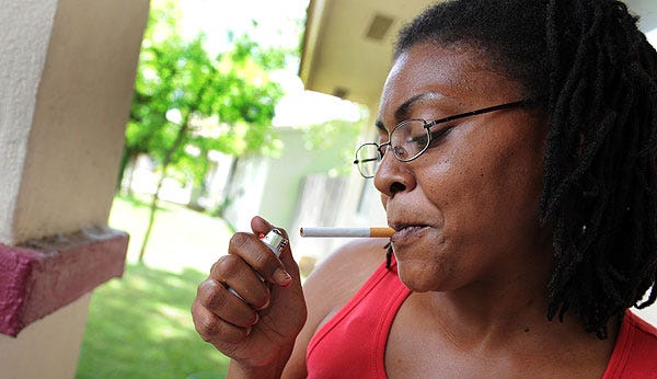 Towanda Gusters, 32, lights up a cigarette outside her house at a public housing development in Thornton last week. “They're interfering with people's rights,” Gusters said of a proposal to ban smoking in such developments. “If we choose to smoke, we choose to smoke.”