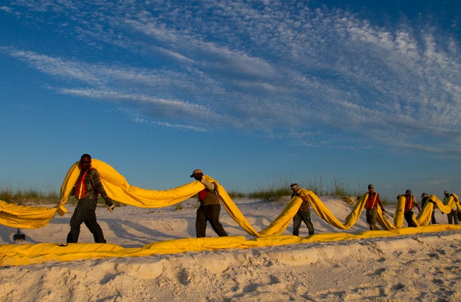 Workers transport hundreds of feet of oil boom down the beach to be attached to boats and pulled to Pensacola Pass to protect the waterway from an oil plume off the coast of Pensacola Beach, Fla., Friday, June 11.