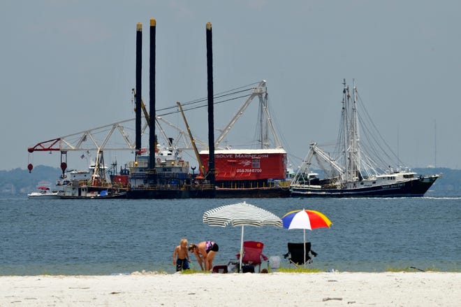 Beachgoers relax as boats clean oil in Pensacola Pass off the Gulf Islands 
National Seashore Saturday.