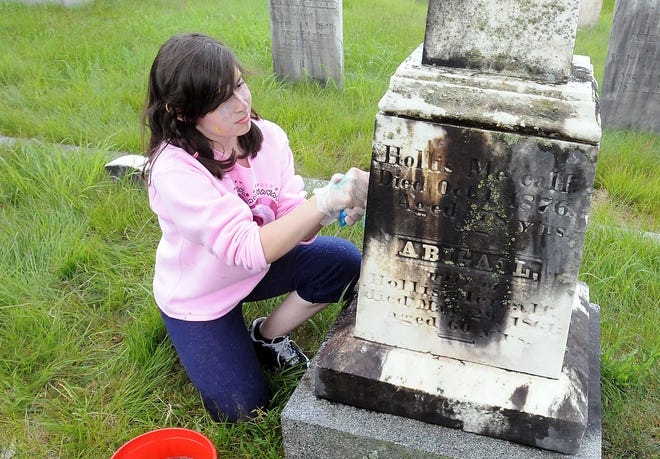 Girl Scout Samantha Reed, 11, scrubs down a headstone in the Oak Hill Cemetery, Thursday in Bellingham.