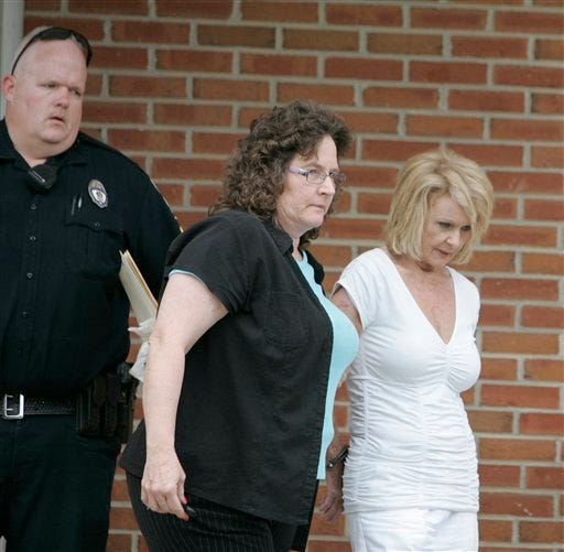 Julia Phillips, right, is escorted from the York Police Department on May 18. Phillips is charged with murder in the death of Melvin Roberts. The Cherokee County Coroner Dennis Fowler has the body of Edward Phillips exhumed Monday after his family requested an investigation of his 1999 death at an Atlanta hospital.