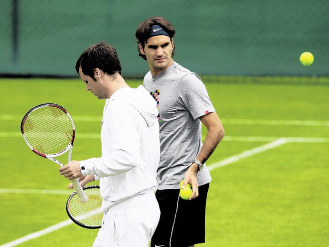 Switzerland's Roger Federer, right, walks with an unidentified player during a practice session at the All England Lawn Tennis Championships at Wimbledon, Sunday, June 20, 2010.