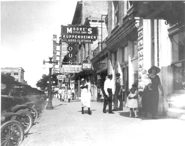 Moore's style shop at 207 East Main St. dominates this 1924 photo. The same area now is shaded by trees. Most of the old building still exists.