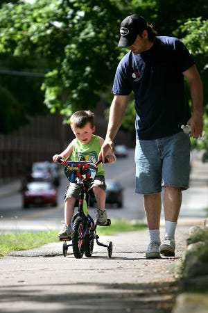 Dustin Cumberland, 4, of Hopedale works on his pedaling skills while his dad, Frank, teaches the boy how to ride a bike down Hopedale Street in Hopedale Wednesday.