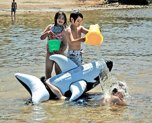 Mackenzie Rintimaki, 7, and Tyler Rintimaki, 9, drench their friend Aaron Cox, 9, and the whale he was riding on during a recent visit to the beach at Sherman Park. No animals were injured during the filming of this incident.