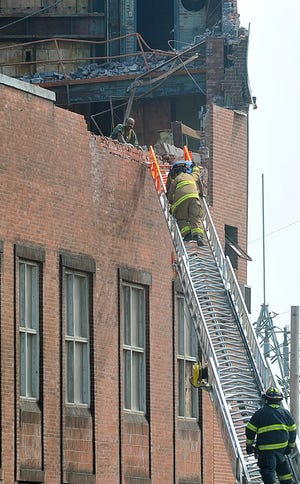 Firefighters bring an injured construction worker down a ladder after wind caused a partial collapse at the former Taunton Municipal Lighting Plant building, which was being dismantled Thursday, June 24, 2010, in Taunton.