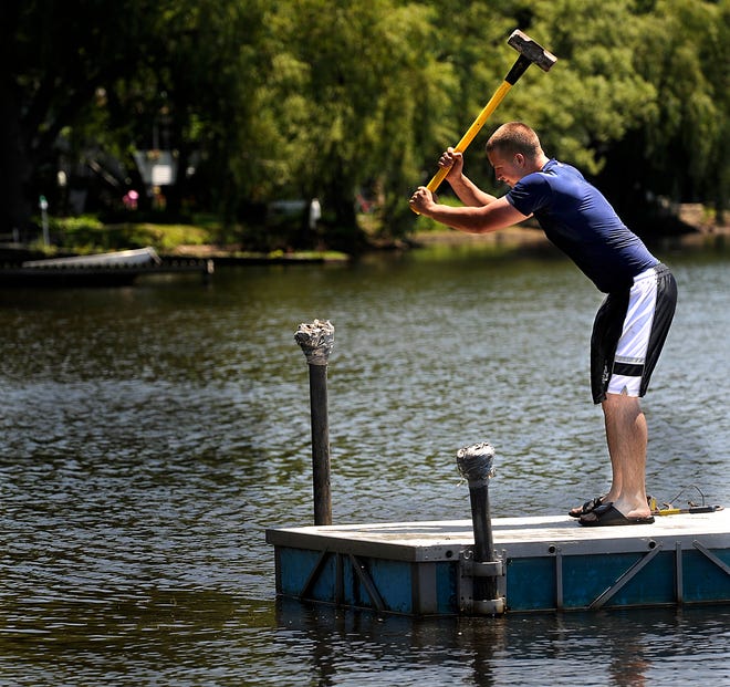Framingham Parks and Recreation worker James Davis hammers into place the floating dock at Lake Waushakum yesterday. The beach opened for the season Thursday.