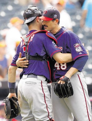 Minnesota's Carl Pavano (48) gets a hug from catcher Joe Mauer after throwing a 3-hit, complete game shutout against the Mets at Citi Field in New York on Saturday afternoon.