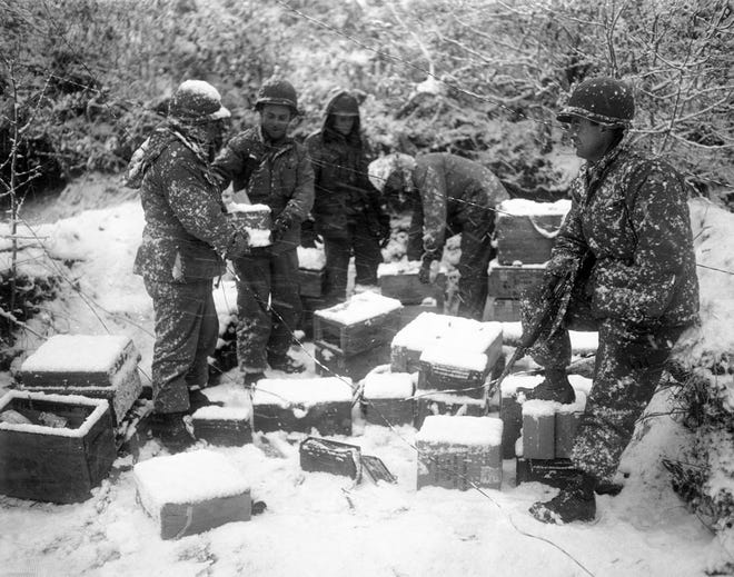 Troops of Oklahoma's 45th Division stack supplies on the western front in Korea despite falling snow, Jan. 2, 1952. From Left to right are Cpl. James A. Burns, Coleman, Texas, M/Sgt. Floyd D. Ford, Gowen, Okla.; Pfc. Weldon K. Jester, Memphis, Tenn.; Pfc. Marvin Charleston, Stony Point, New York, and 2nd Lt. Charles Barry, McAlester, Okla. The 45th recently went into the line after training in Japan.