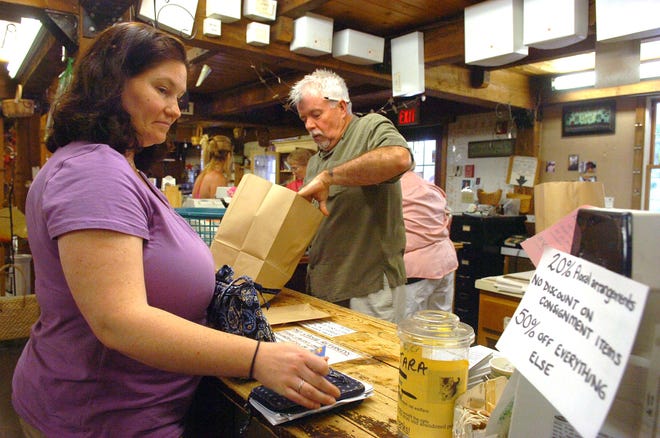 Howard Dempsey, right, rings up Kate Michaud of Bridgewater at the cash register as he places her item into a paperbag at Dempsey's Village Barn, which is closing after 30 years in West Bridgewater.