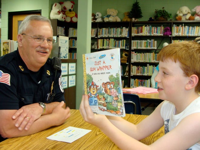 Metamora Police Chief Mike Todd smiles as he listens to Skyler Hessinger, 7, a first-grader at Metamora Grade School, read to him. Todd initiated a program which brings Metamora High School students into the grade school latchkey program as volunteers.
