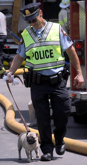 Police Sgt. Mark St. Hilaire walks a dog to safety who was rescued by firefighters at the Kansas Street fire Tuesday.