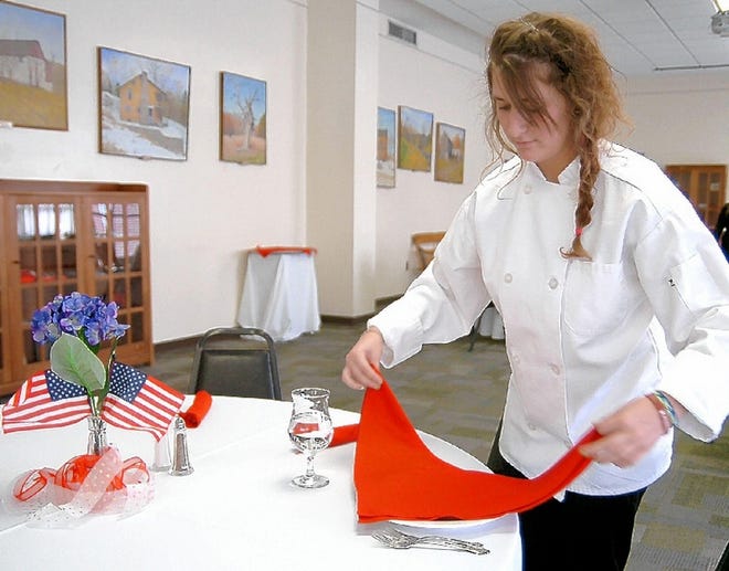 Allison Depompeis readies a napkin in preparation for the etiquette dinner held at East Stroudsburg University recently. The event shows students how to behave during job-interview business dinners.
