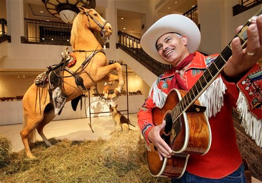 Gil Perez, right, a doorman at Christies auction house, wears an outfit and holds a guitar belonging to Roy Rogers as he stands alongside the preserved remains of Rogers' horse "Trigger" and dog "Bullet" at the New York auction house, Friday, July 9, 2010. Christie's held a preview Friday of an upcoming auction of items from the now-closed Roy Rogers and Dale Evans Museum in Branson, Mo.