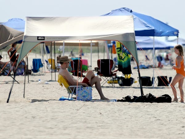 Beach goers escape the sun at Oak Island under collapsable shade canopies on July 7, 2010. The canopies can be a nuisance for emergency responders on the beach.