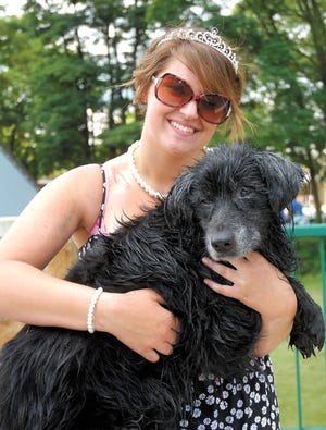 Amiee Jarzenski, 16, the 2nd Attendant on the Canal Fulton Olde Canal Days Festival’s Queens Court, holds the black dog that she rescued from the Tuscarawas River on Saturday afternoon. The dog, which hasn’t been identified, was taken in by the Humane Society.