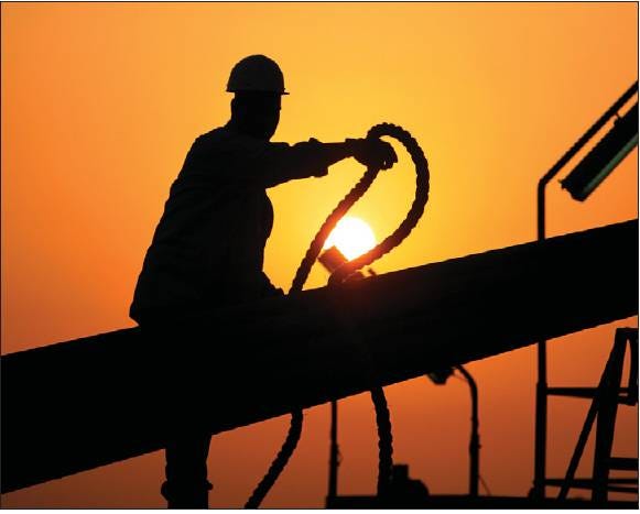 OIL RIG: An unidentified oilfield worker ties pipes to be raised on an oil rig as the sun sets on July 7 in the Persian Gulf desert oil field of Sakhir, Bahrain. Oil prices climbed above $77 a barrel on Tuesday, as the global recovery got a boost on two fronts after weeks of mixed economic news.