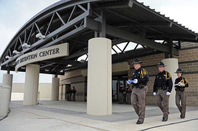 Lubbock County Sheriff's Office Honor Guard members left to right; Deputy Kortney Garrett, Deputy James Baucum and Deputy Jennifer Cruz carry the ceremonial ribbon and scissors to the front of the new Lubbock County Detention Center Wednesday morning. (John A. Bowersmith/Lubbock Avalanche-Journal)