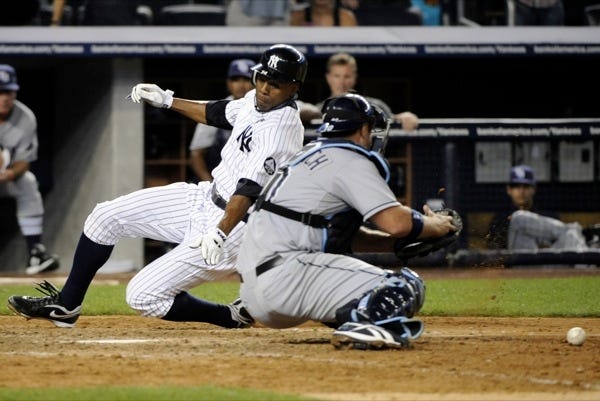 New York Yankees' Curtis Granderson, left, scores the winning run as Tampa Bay Rays catcher Kelly Shoppach drops the ball during the ninth inning of a baseball game Friday, July 16, 2010, at Yankee Stadium in New York. The Yankees won 5-4.