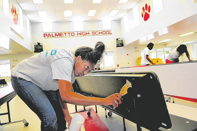 Mosha Jerome, 16, of Palmetto, scrapes gum off the bottom of cafeteria 
tables while working at Palmetto High School on Thursday as part of a summer 
job program offered by the school district. The job, which pays $7.25 an 
hour, also includes algebra class.