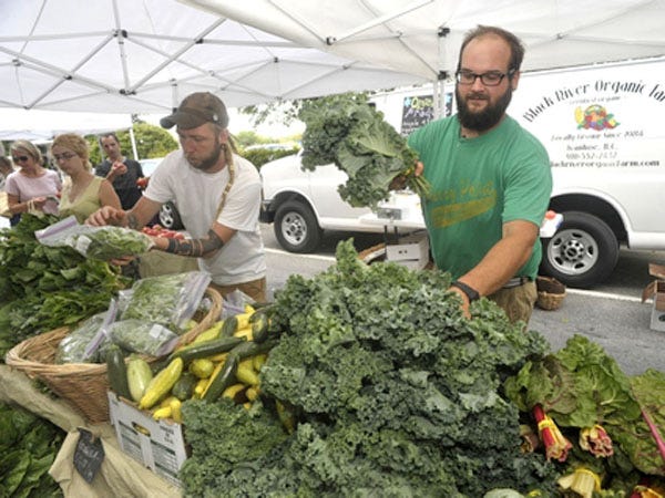 Markter manager for Black River Organic Farms Mike Slaton straighten's up some fresh vegetables at Wilmington's Farmers Market in May.