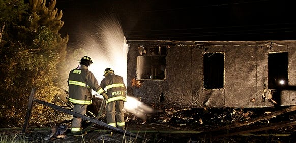 North Myrtle Beach firefighters hose down a burned mobile home and plane wreckage inside the Creekside Mobile Home Park on Wednesday, July 14, 2010. A private plane slammed into the ground and then crashed into the mobile home shortly before 9 p.m., North Myrtle Beach officials said. No one in the mobile home suffered serious injuries. Photo by The Sun News