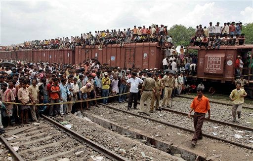 Local residents watch as rescue workers search for survivors at the site of an accident at Sainthia station, about 125 miles (200 kilometers) north of Calcutta, India, Monday, July 19, 2010. A speeding express train collided with a passenger train at the station in eastern India early Monday, mangling the carriages and killing scores of people, railway police said.