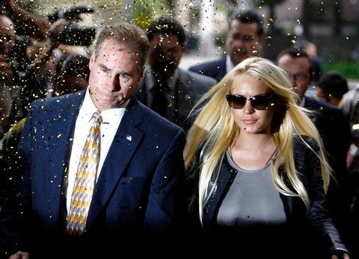 Confetti flies as Lindsay Lohan, with an unidentified man, arrives at the Beverly Hills courthouse Tuesday, July 20, 2010.