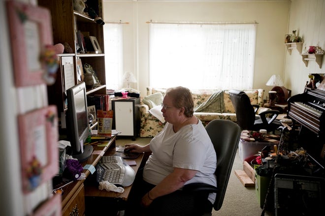 Afton England, 65, whose medical problems prevent her from walking or 
standing for long periods of time, sits at the computer in her trailer home 
in Hillsboro, Oregon.NEW YORK TIMES / LEAH NASH