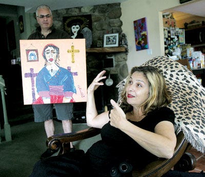 Photo by Amy Paterson/New Jersey Herald - Nina Palumbo talks about her latest painting, held by her husband Sal. The painting, which she plans to give to her doctor, was inspired by the trips to Mexico for stem cell treatments.