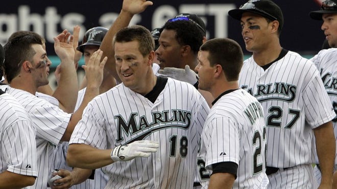 The Florida Marlins celebrate after Wes Helms (18) hit a bases-loaded game-winning single in the 11th inning to beat the Braves on Sunday, July 25, 2010, in Miami Gardens.