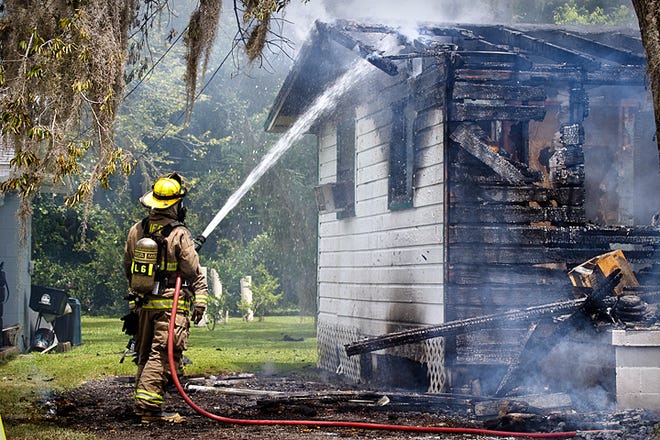 A St. Johns County firefighter sprays water on hot spots in a house that caught fire on Ashland Street in Hastings Saturday afternoon. By CHRISTOPHER KIMBALL, Special to The Record