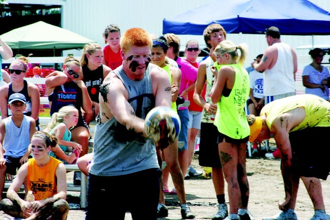 Monmouth-Roseville's Jon Strickler serves during mud volleyball competition at the Warren County Fair.