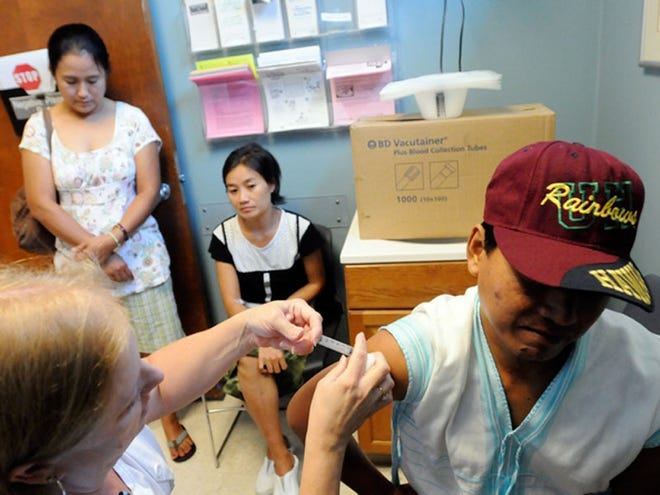 Nay Tha, 40, receives a series of immunizations from LPN Kathy Bundy as his wife Eh Blut Paw, 35,(sitting) and interpreter Ehlia Naw looks on at the New Hanover County health department.