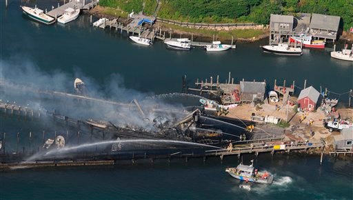 A U.S. Coast Guard building, pier and truck on Martha's Vineyard are doused by firefighters after catching fire at Menemsha Harbor in Chilmark, Mass., Monday, July 12, 2010. The U.S. Coast Guard says a massive blaze has torched its boathouse, pier as well as a truck and trailer on Martha's Vineyard, forcing people to evacuate the 22-person facility by boat.