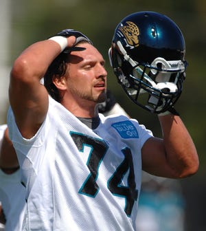 Jacksonville Jaguars defensive end Aaron Kampman puts on his helmet Friday during the first practice session of training camp. By RICK WILSON, Morris News Service
