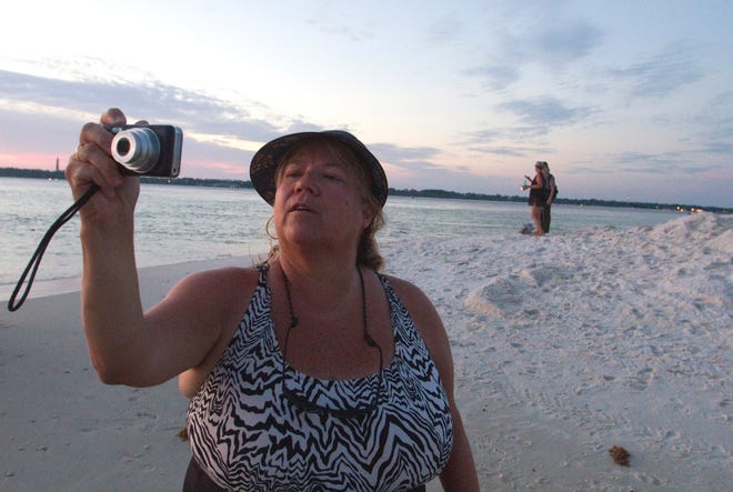 Dolores Pittman, of Pensacola, takes a photo off the coast of Santa Rosa Island in Pensacola Pass as crews work to set up oil booms to protect the waterway from an oil plume off the coast of Pensacola Beach, Fla., Friday, June 11th, 2010.