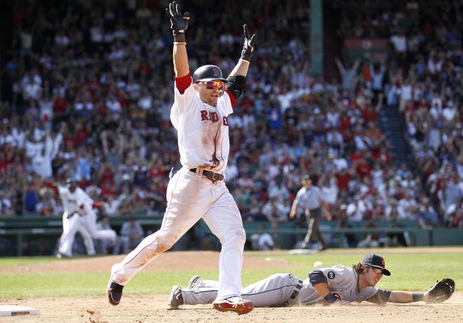 Red Sox shortstop Marco Scutaro celebrates his game-winning bunt single that scored Darell McDonald (background) after Tigers pitcher Robbie Weinhardt threw wild past first base.