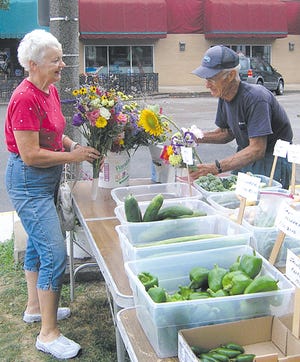 Roland Schwanke, Gridley, sells flowers to Sandra Degenhart, Pontiac, at Saturday’s downtown Pontiac Farmer’s Market. The markets continue on Saturday mornings through October.