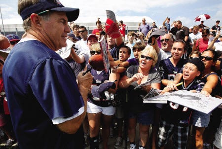New England Patriots head coach Bill Belichick, left, signs autographs during a break in Monday’s practice at Gillette Stadium in Foxborough, Mass.