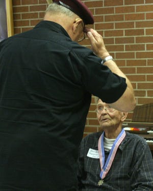 Jerry Fjeld, President of the International War Veterans Alliance, salutes Art Sorum after placing a medal around his neck during a ceremony yesterday at Heartland Care Center.