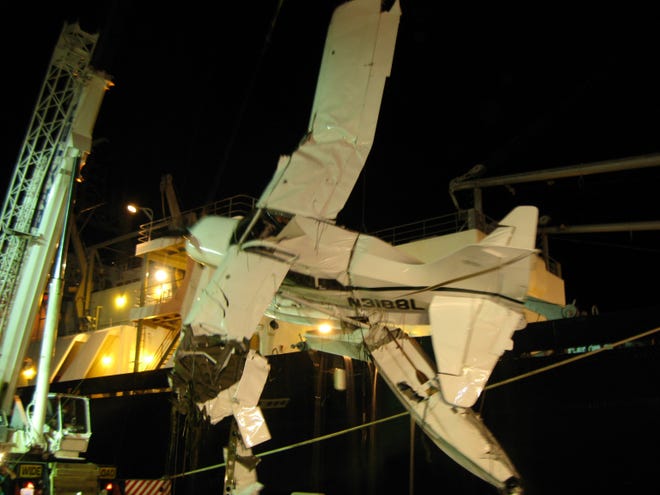 A badly damaged seaplane is hoisted from the Cape Cod canal Monday night.